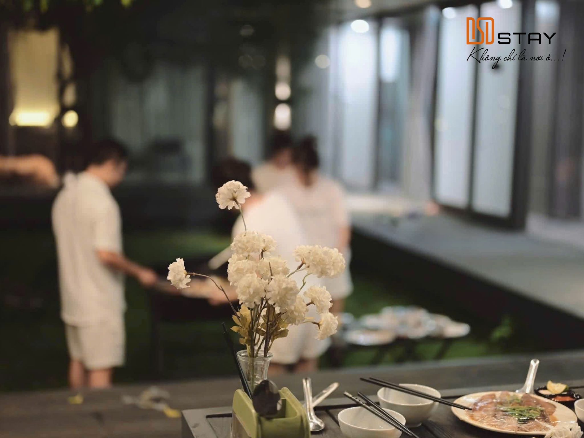 Các thành viên trong gia đình cùng dùng bữa và trò chuyện trong buổi tiệc BBQ ngoài trời tại DSD Stay